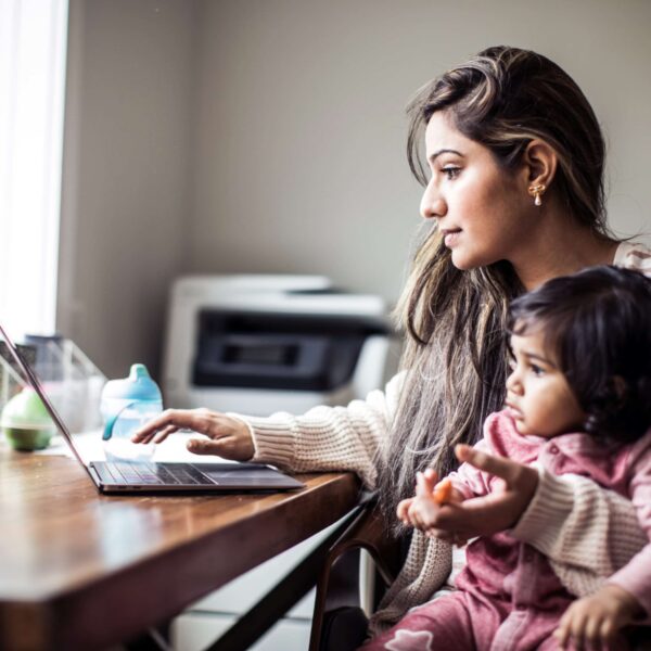 Mother multi-tasking with infant daughter in home office